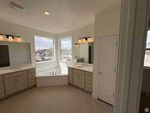 Full bath featuring two vanities, a bath, visible vents, and a sink