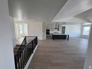 Hallway with hardwood / wood-style flooring, baseboards, a textured ceiling, and a wealth of natural light