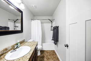 Bathroom featuring shower / bath combo, vanity, baseboards, toilet, and visible vents