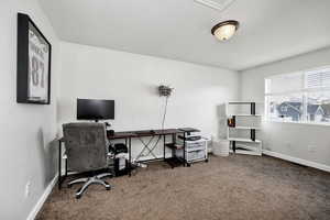 Carpeted home office featuring baseboards