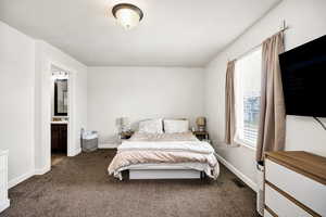 Bedroom with connected bathroom, baseboards, dark colored carpet, and visible vents