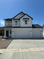 View of front of property featuring driveway, roof with shingles, board and batten siding, and a garage