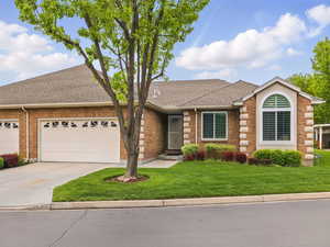 Ranch-style home featuring roof with shingles, brick siding, concrete driveway, and a front lawn