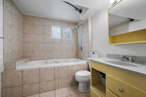 Bathroom featuring tiled shower / bath combo, tile patterned flooring, vanity, and toilet