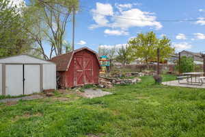 View of yard featuring an outdoor structure, a storage unit, a patio area, and fence