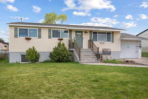 View of front of property featuring an attached garage, a front lawn, and concrete driveway