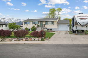 View of front of property with a mountain view, driveway, a shingled roof, and a garage