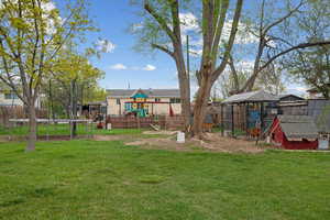View of yard featuring an outbuilding, exterior structure, a playground, fence, and a trampoline