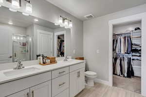 Bathroom with double vanity, a sink, visible vents, and a stall shower