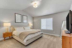 Bedroom featuring baseboards, vaulted ceiling, and light colored carpet