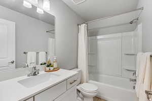 Full bathroom with shower / bath combo with shower curtain, visible vents, vanity, and toilet