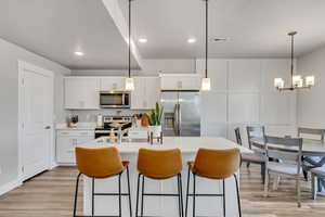Kitchen with light countertops, white cabinetry, light wood finished floors, and stainless steel appliances