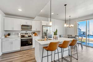 Kitchen with an island with sink, a kitchen breakfast bar, stainless steel appliances, and light wood-style flooring