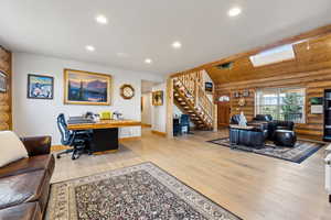 Living area featuring stairway, light wood-style flooring, baseboards, log walls, and recessed lighting
