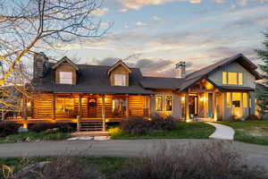 Log home with a chimney, roof with shingles, board and batten siding, and a lawn