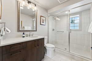 Bathroom featuring tile patterned flooring, a shower stall, toilet, and vanity