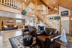 Living area featuring high vaulted ceiling, wood finished floors, stairs, and wood ceiling