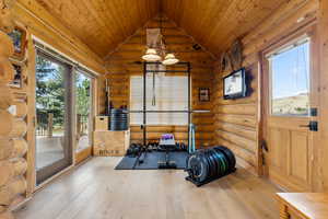 Workout room featuring wooden ceiling, vaulted ceiling, log walls, and hardwood / wood-style floors