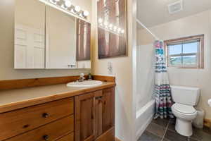 Full bath featuring tile patterned floors, toilet, visible vents, shower / tub combo with curtain, and vanity