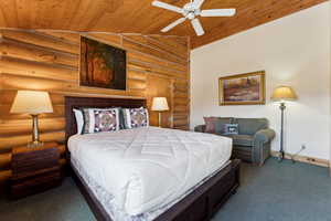 Bedroom with vaulted ceiling, carpet, wooden ceiling, baseboards, and log walls
