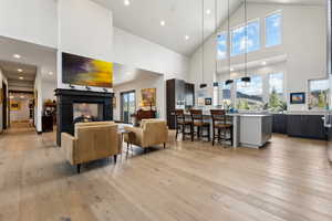 Living area featuring high vaulted ceiling, a multi sided fireplace, and light wood-style flooring