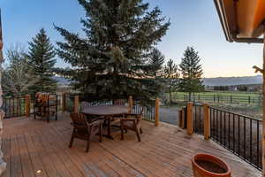 Deck with a rural view, outdoor dining area, and a mountain view
