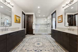 Full bathroom featuring two vanities, a stall shower, and a sink