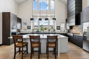 Kitchen featuring high vaulted ceiling, a breakfast bar area, stainless steel appliances, and a sink