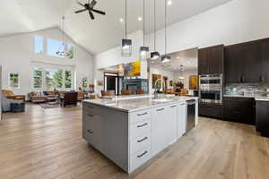 Kitchen with high vaulted ceiling, modern cabinets, open floor plan, and a sink
