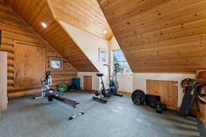 Exercise room with wood ceiling, vaulted ceiling, and log walls