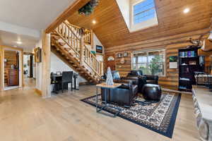 Living area featuring recessed lighting, log walls, stairway, hardwood / wood-style flooring, and high vaulted ceiling
