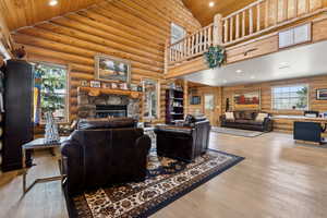 Living room featuring wood ceiling, hardwood / wood-style flooring, high vaulted ceiling, and rustic walls