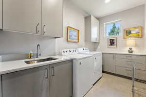 Laundry area featuring washer and clothes dryer, a sink, light tile patterned flooring, recessed lighting, and cabinet space