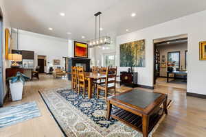 Dining space with recessed lighting, light wood-style floors, a tiled fireplace, and an inviting chandelier