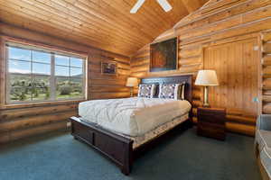 Bedroom with lofted ceiling, log walls, wood ceiling, and carpet
