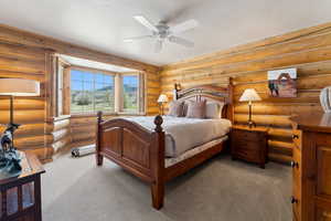 Bedroom with carpet flooring, ceiling fan, and log walls