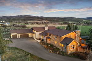 Exterior space with a chimney, driveway, a garage, log exterior, and roof with shingles