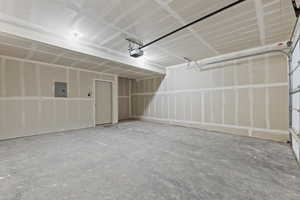 Garage featuring electric panel and a garage door opener