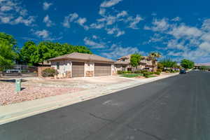 View of front of house featuring driveway, stone siding, an attached garage, fence, and stucco siding