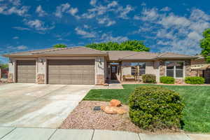 Prairie-style home with a front lawn, driveway, stone siding, an attached garage, and stucco siding