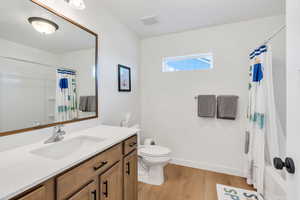 Full bathroom featuring baseboards, wood finished floors, toilet, and vanity