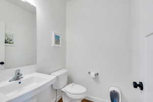Half bath featuring baseboards, toilet, and a sink