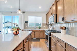 Kitchen featuring a sink, brown cabinetry, decorative backsplash, stainless steel appliances, and light wood-style flooring