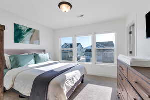 Bedroom with visible vents, baseboards, and light carpet