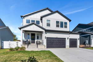 View of front of property featuring concrete driveway, a front lawn, board and batten siding, covered porch, and an attached garage