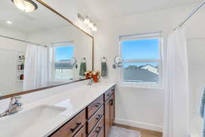 Bathroom featuring curtained shower, baseboards, a sink, and double vanity