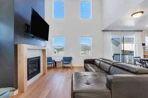Living area with light wood finished floors, plenty of natural light, a tiled fireplace, and a high ceiling