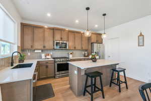 Kitchen featuring a sink, decorative backsplash, a breakfast bar area, appliances with stainless steel finishes, and a kitchen island