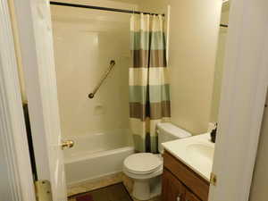 Full bath with shower / bath combo, vanity, tile patterned flooring, and toilet