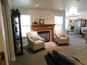 Living room with a fireplace, a chandelier, carpet flooring, and recessed lighting